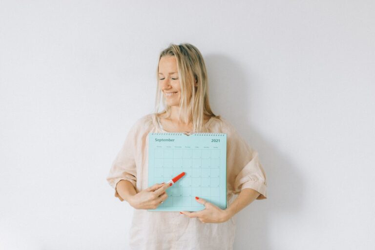 Femme souriante montrant une date sur un calendrier pour illustrer le calcul semaine de grossesse