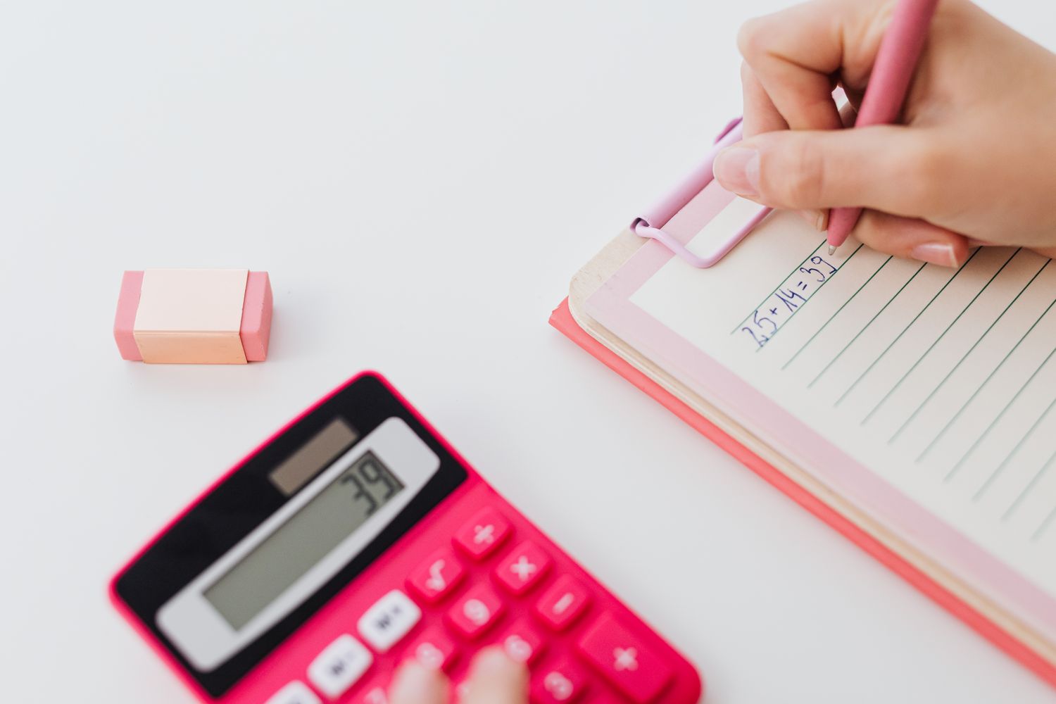 Mains utilisant une calculatrice et notant des calculs sur un carnet pour convertir des semaines en mois de grossesse