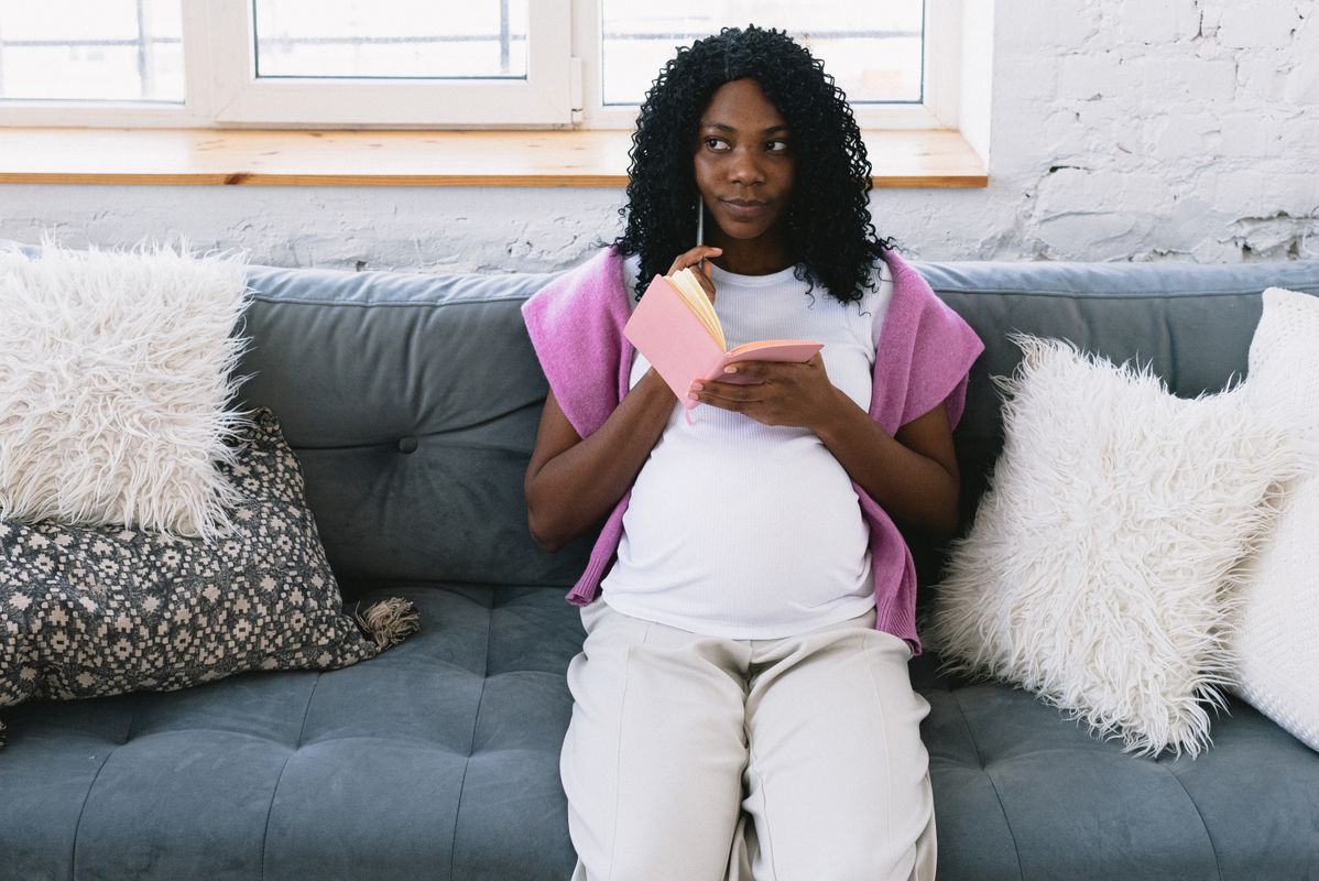 Femme enceinte notant le calcul de ses semaines de grossesse dans un carnet
