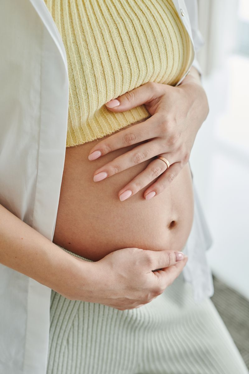 Gros plan sur les mains d'une femme enceinte posées sur son ventre en fin de grossesse