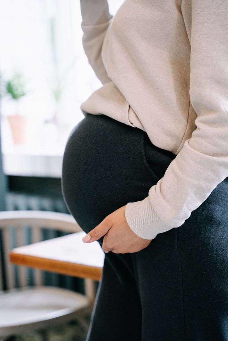 Femme enceinte de profil, une main posée sur son ventre, illustration des changements hormonaux