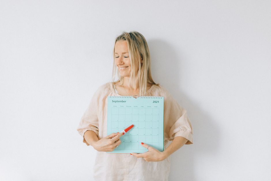 Femme souriante pointant une date sur un calendrier de grossesse