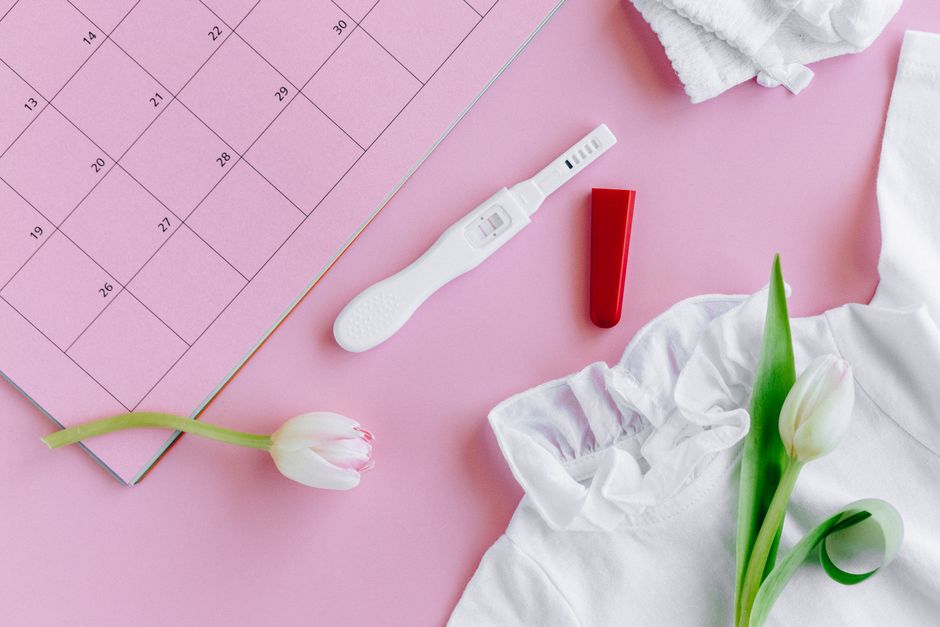 Test de grossesse positif posé sur un calendrier, symbole du calcul des semaines de grossesse