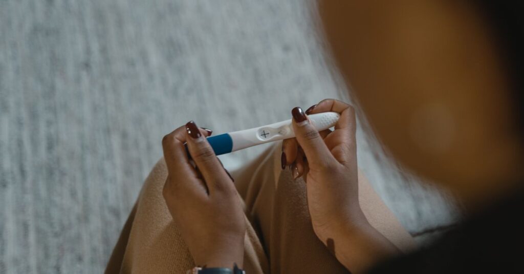 Test de grossesse positif tenu en main, illustrant le prix d'un test de grossesse