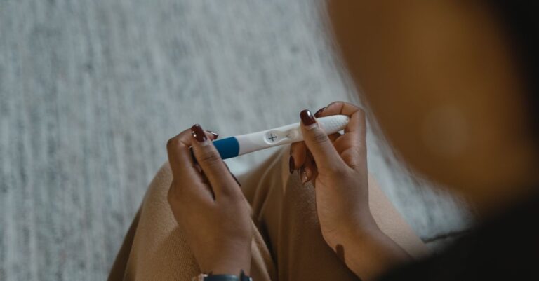 Test de grossesse positif tenu en main, illustrant le prix d'un test de grossesse