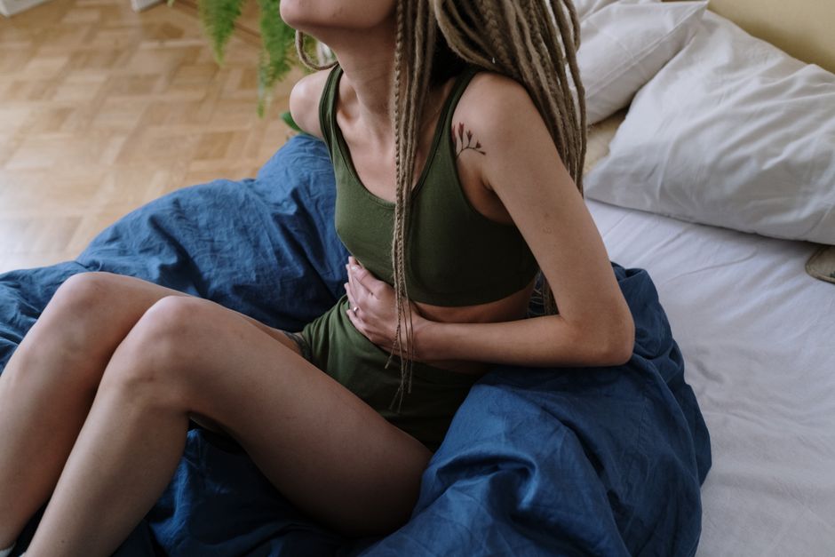 Femme enceinte assise tenant son ventre avec inconfort
