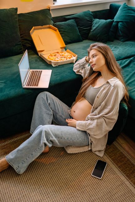 Femme enceinte mangeant une part de pizza à la maison