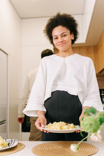 Femme enceinte souriante avec une assiette de pâtes