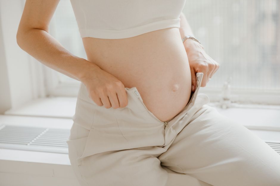 Femme enceinte de 2 mois ajustant son pantalon