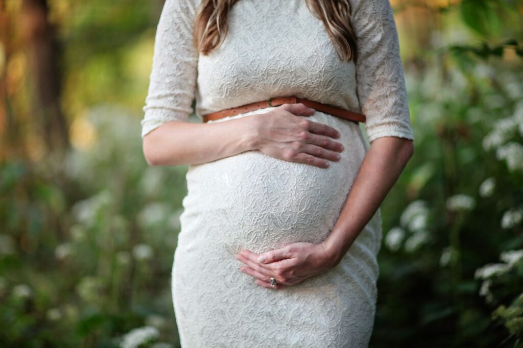 Femme enceinte tenant le bas de son ventre, zone où se porte le bola de grossesse