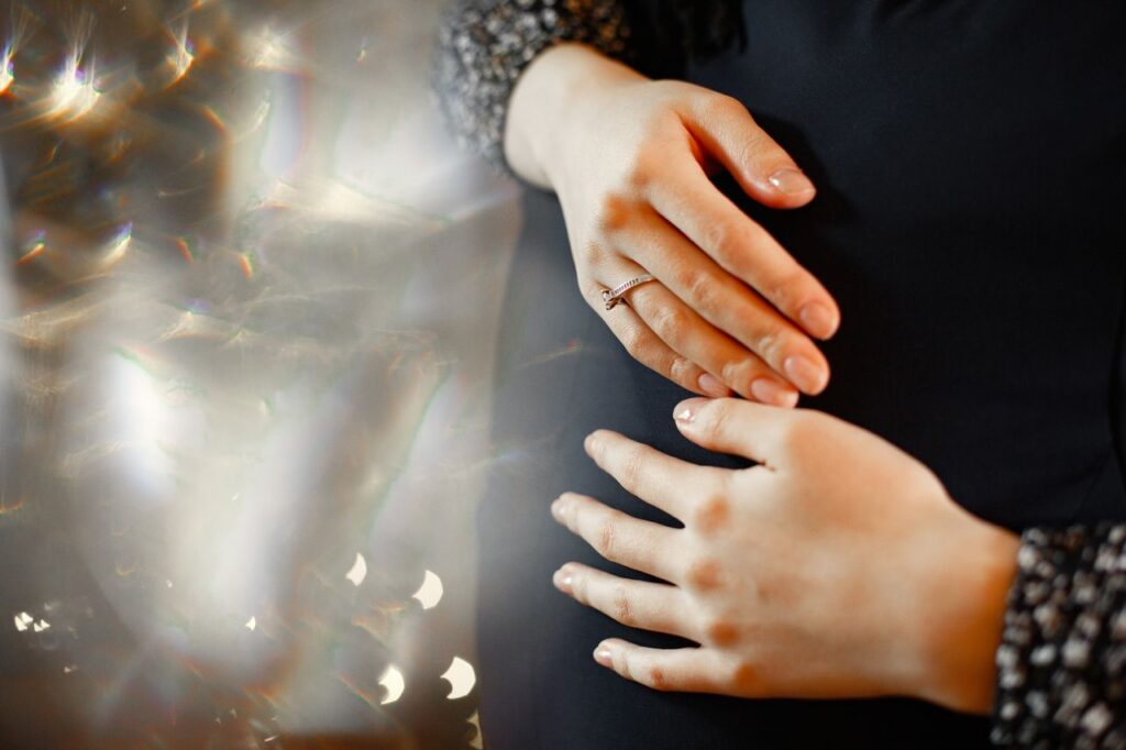 Femme enceinte les mains posees sur son ventre arrondi
