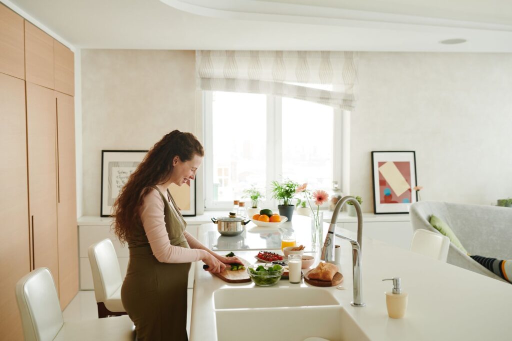 Femme enceinte coupant des légumes dans sa cuisine